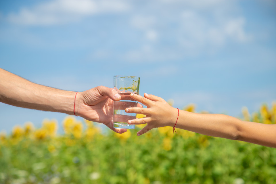 Glas water wordt overgegeven tussen 2 handen